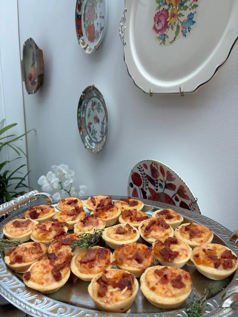 Bandeja prateada com mini quiches de queijo e bacon